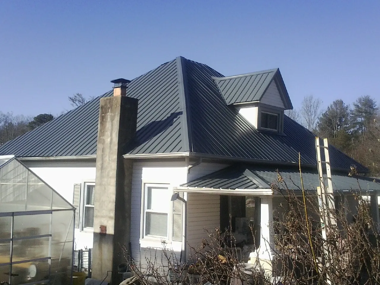 Dark blue standing seam metal roof on a white farmhouse with dormer — Slate & Tile Roof Repair by Roofing Brothers in Meyersdale