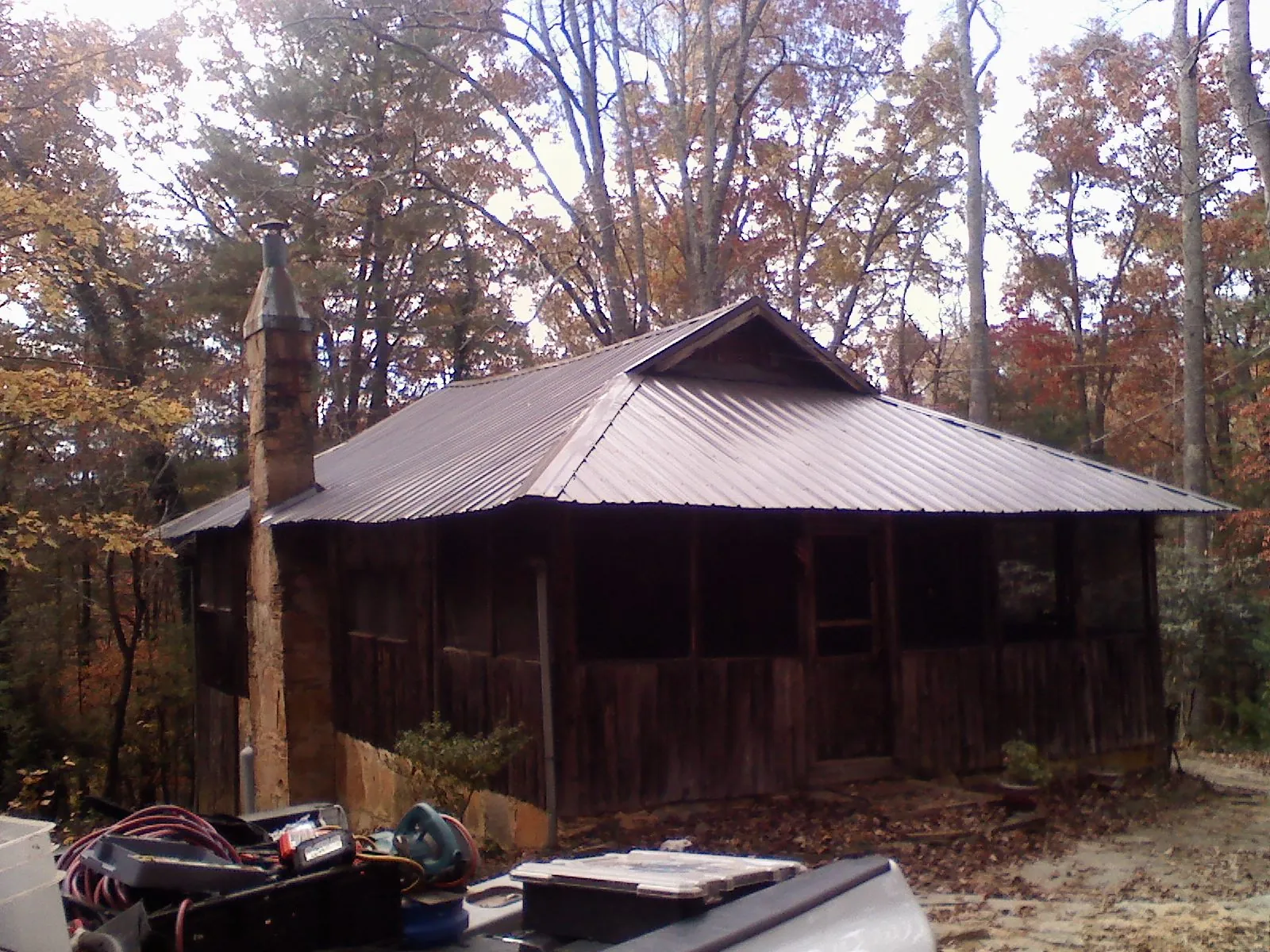 Brown metal hip roof on an old cabin with a stone chimney in Meyersdale