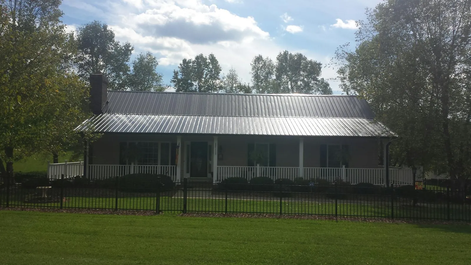 Gray metal roof on a brick ranch with a full width front porch — Gutter Guard Installation work by our crew in Meyersdale