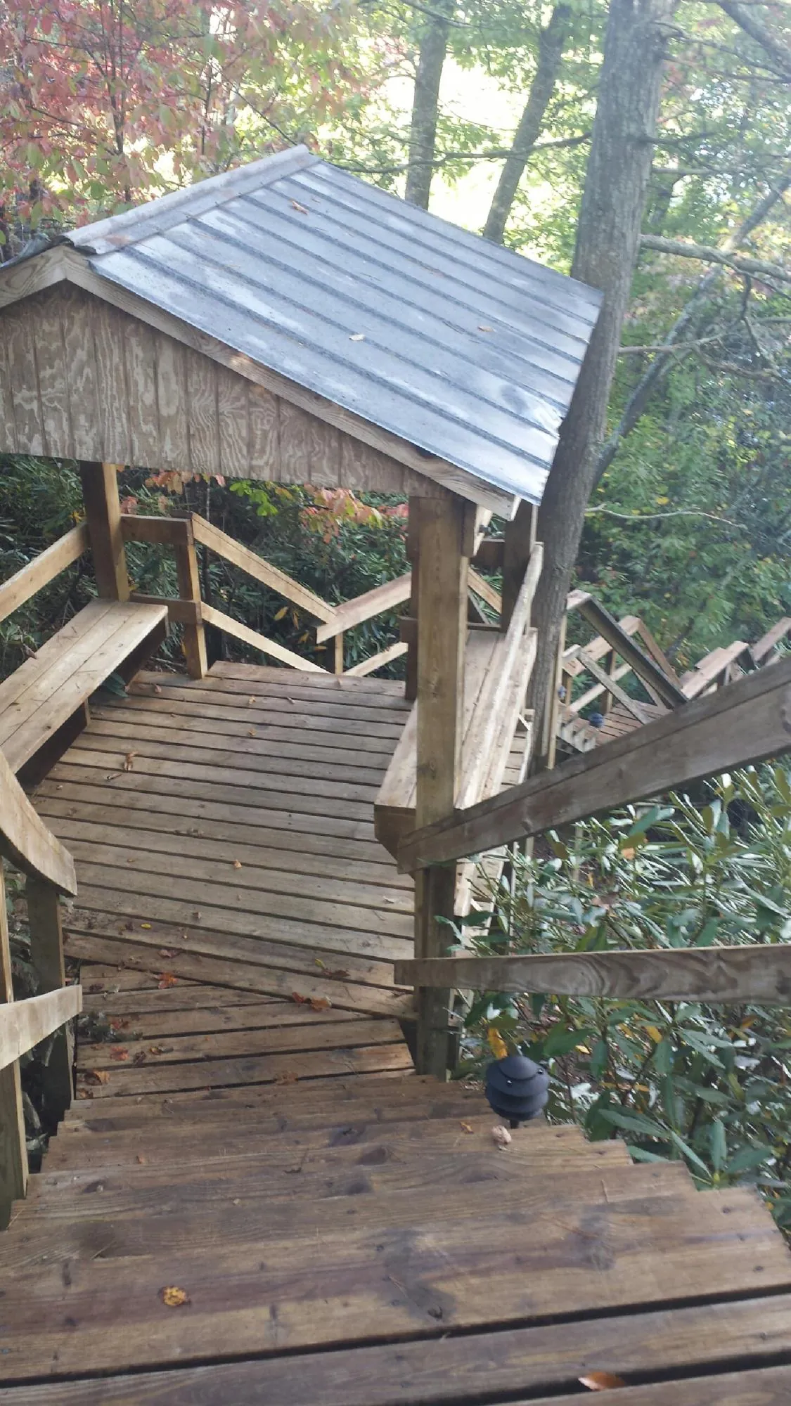 Metal roofed shelter over wooden steps on a wooded walkway — Skylight Repair & Installation work by our crew in Meyersdale