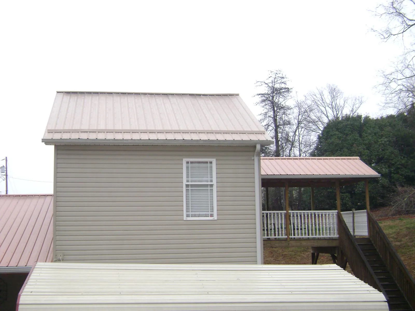 Tan metal roofs on a two story addition and attached porch, from a Roof Replacement job in Meyersdale