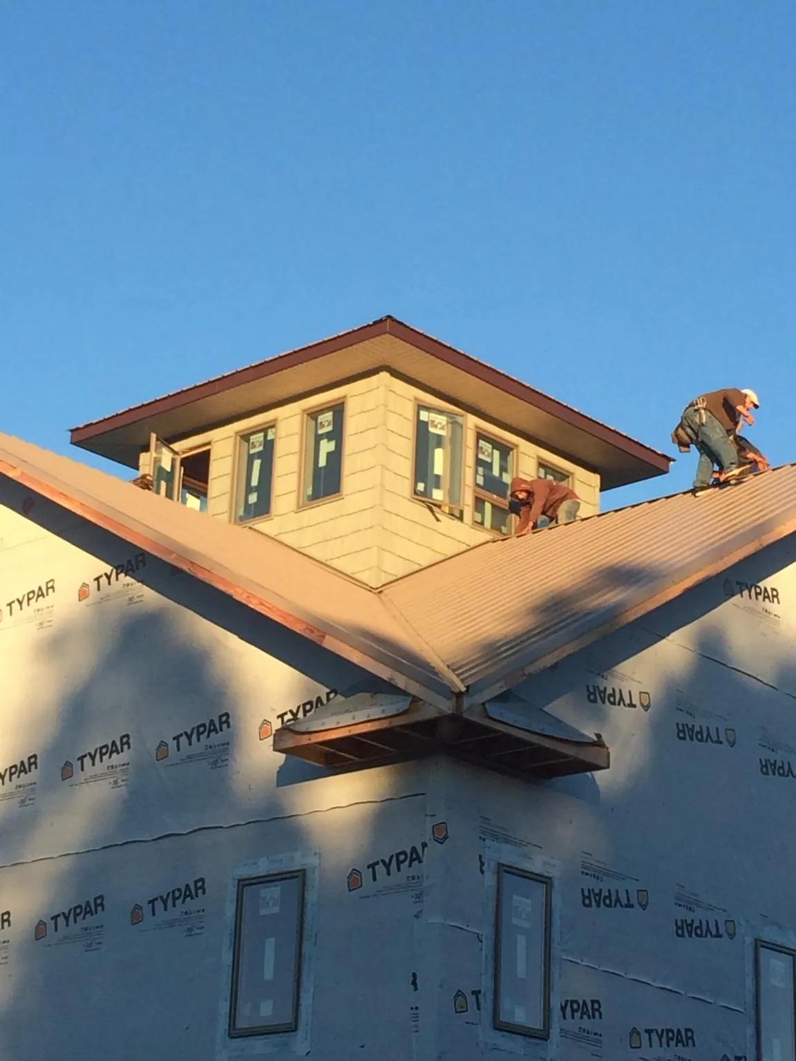 Roofers working around a rooftop cupola on a new metal roof at sunset — Roof Waterproofing in Meyersdale by Roofing Brothers